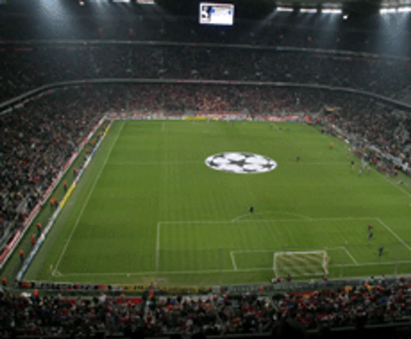 Un stade de football avec une grande écran d'affichage et un logo au centre du terrain de jeu.