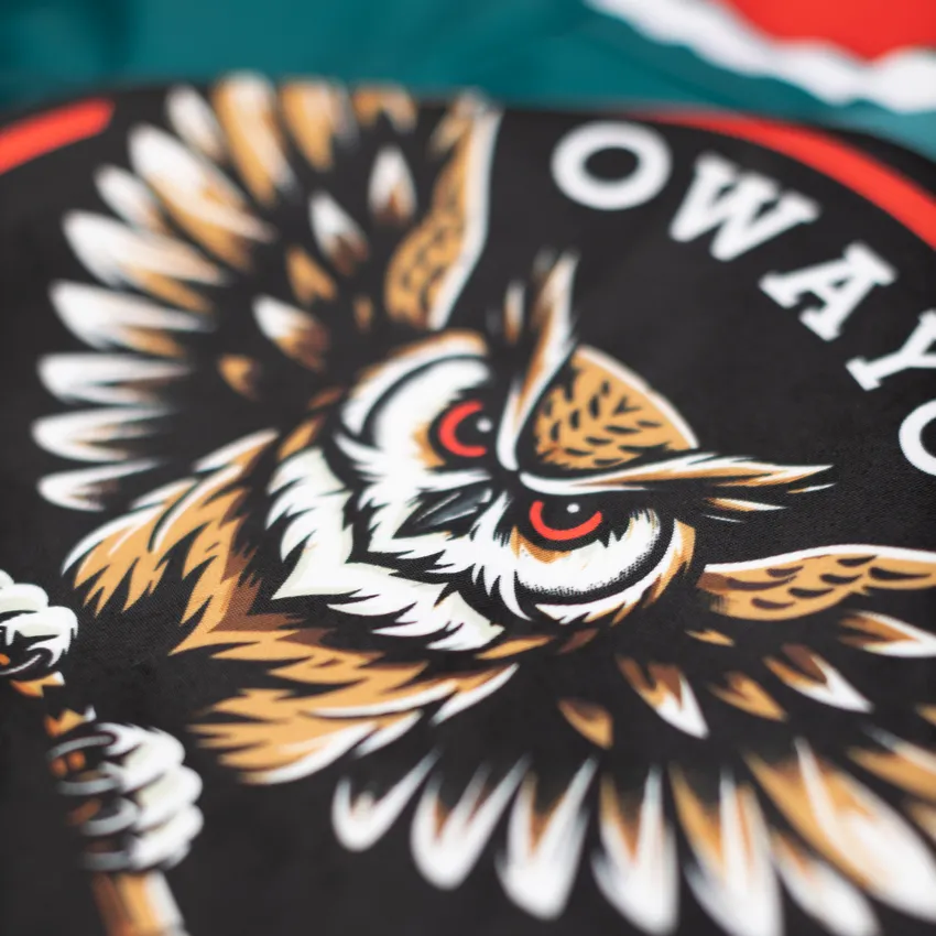 Gros plan d'un design représentant un hibou stylisé et agressif sur un fond noir.