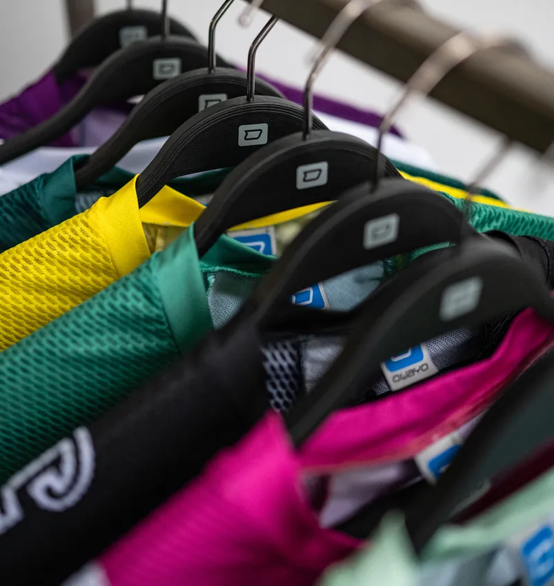 Plusieurs vêtements de sport personnalisés colorés sont suspendus à des cintres noirs.