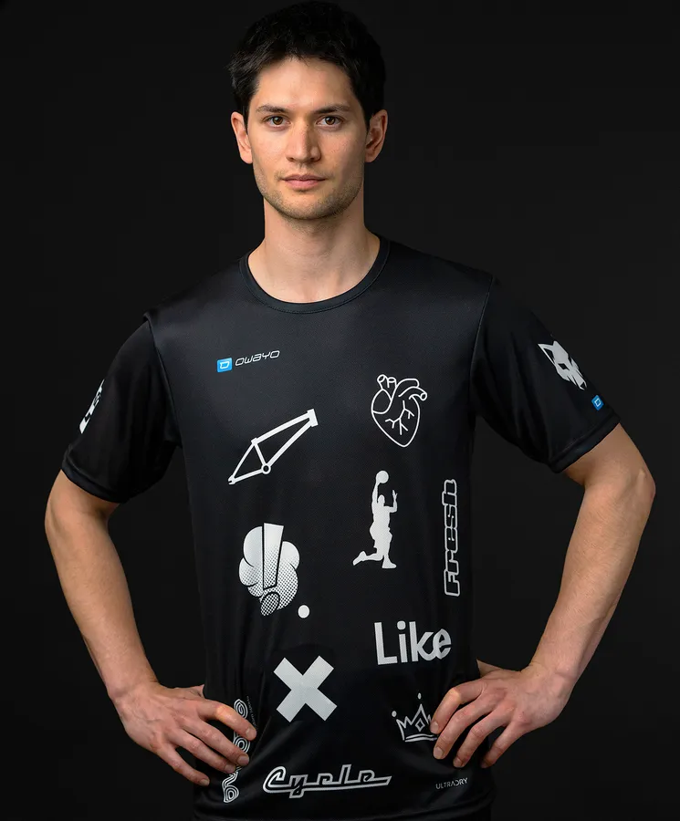 Un homme porte un maillot de sport noir avec divers symboles et logos blancs.