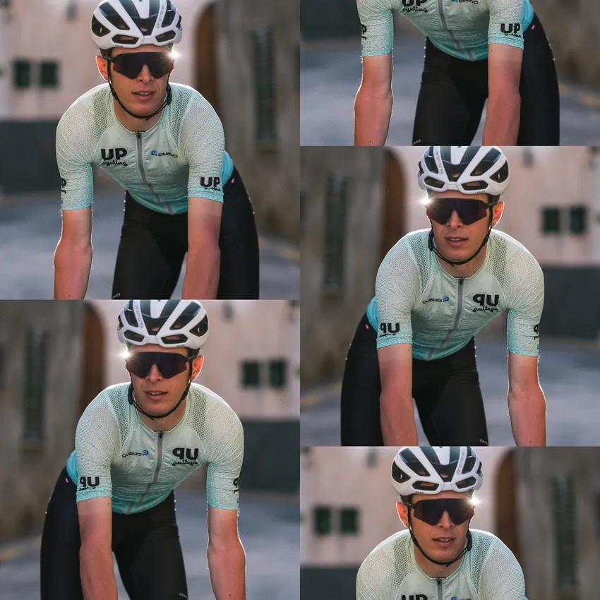 Un cycliste portant un maillot bleu clair à manches courtes et des lunettes de soleil, roulant sur un vélo dans un environnement urbain.